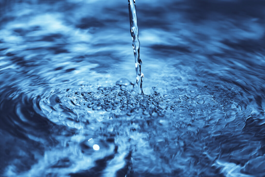 close up of water falling on transparent water surface