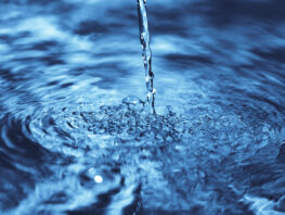 close up of water falling on transparent water surface