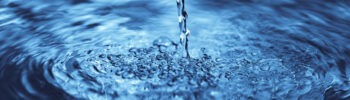 close up of water falling on transparent water surface